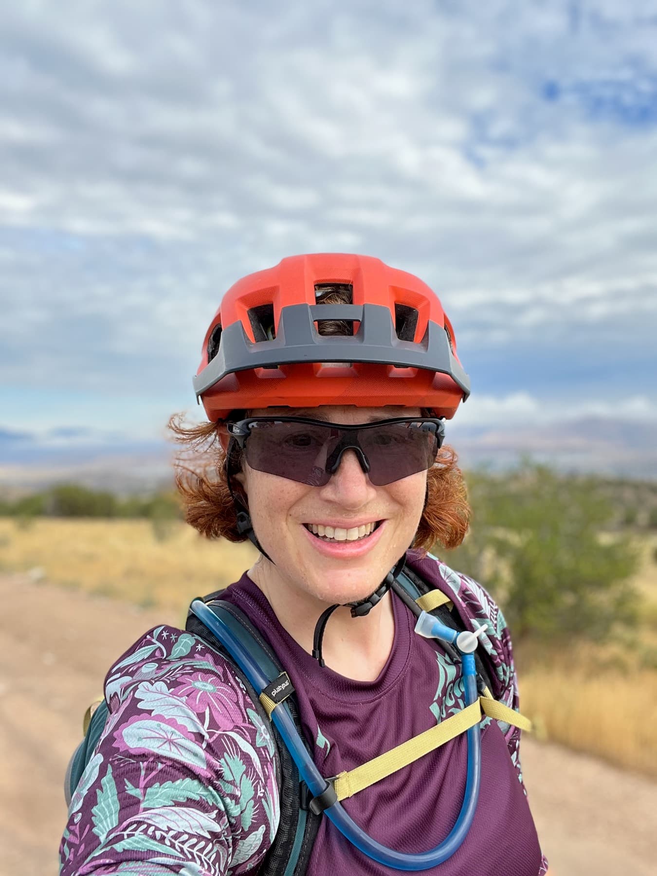 Ann in MTB kit, helmet and sunglasses, desert backdrop.