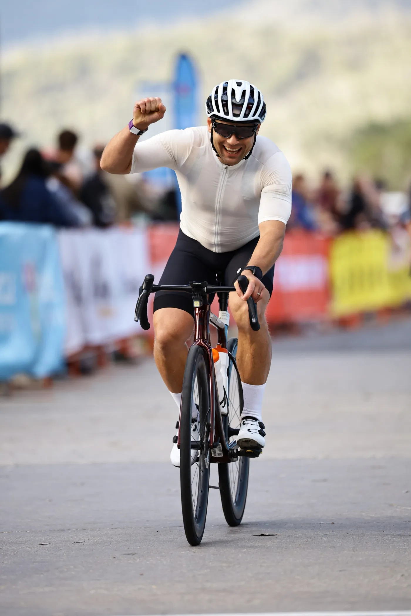 Cyclist celebrating at the finish line, fist raised.